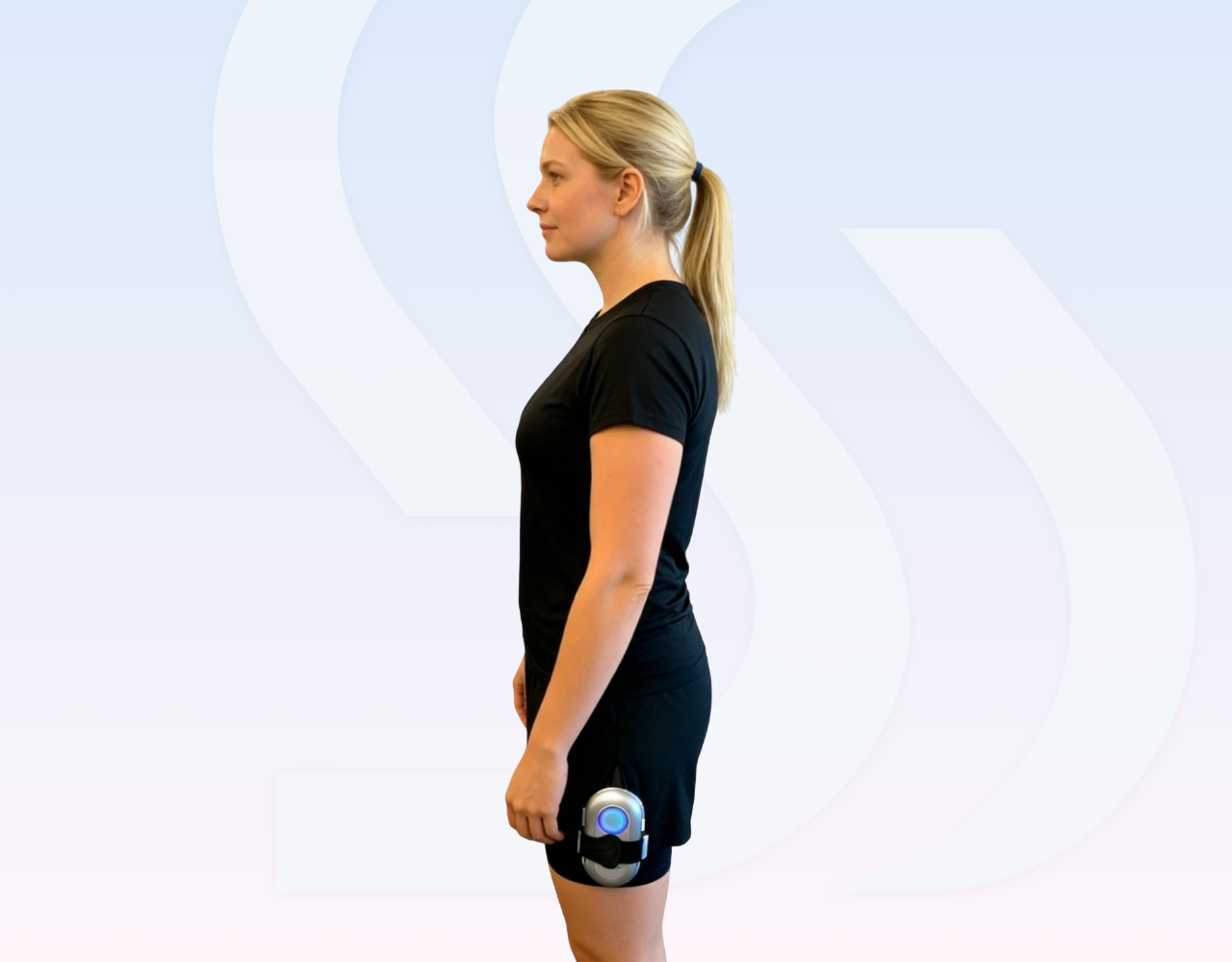 Standing side profile of a woman wearing black clothing with a SweetMyo device attached to her upper thigh on a pale branded background.